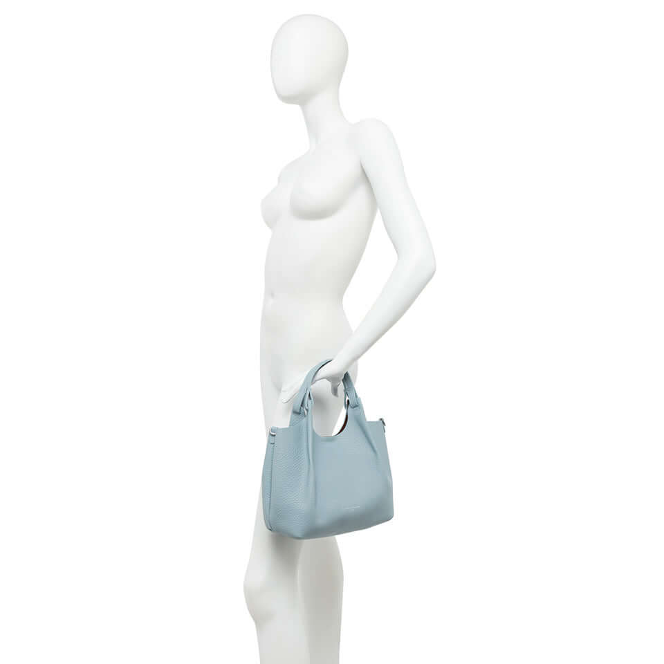 Stylish light blue DUA handbag displayed on a mannequin, showcasing its versatile design and modern aesthetic.