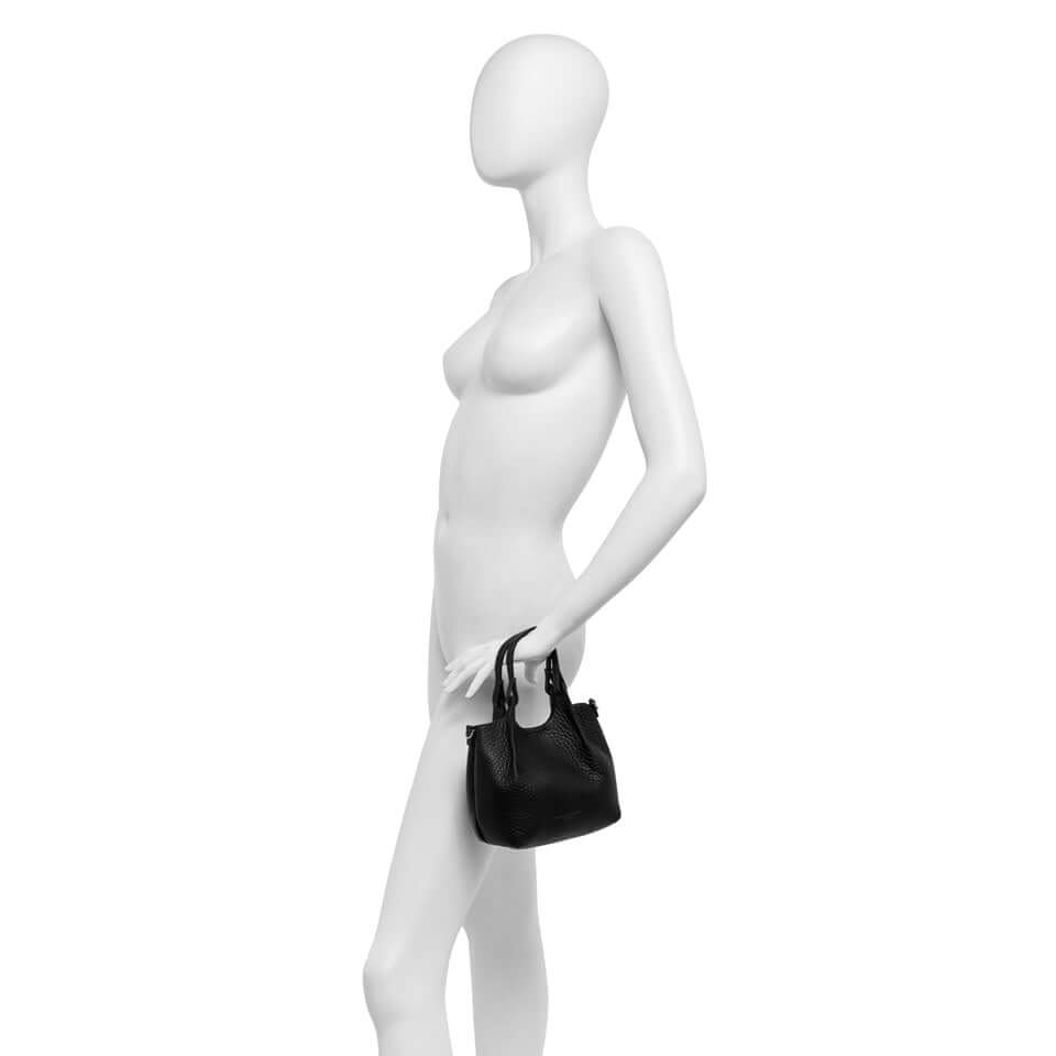 Black DUA handbag on mannequin showcasing simple, contemporary design and leather handles.