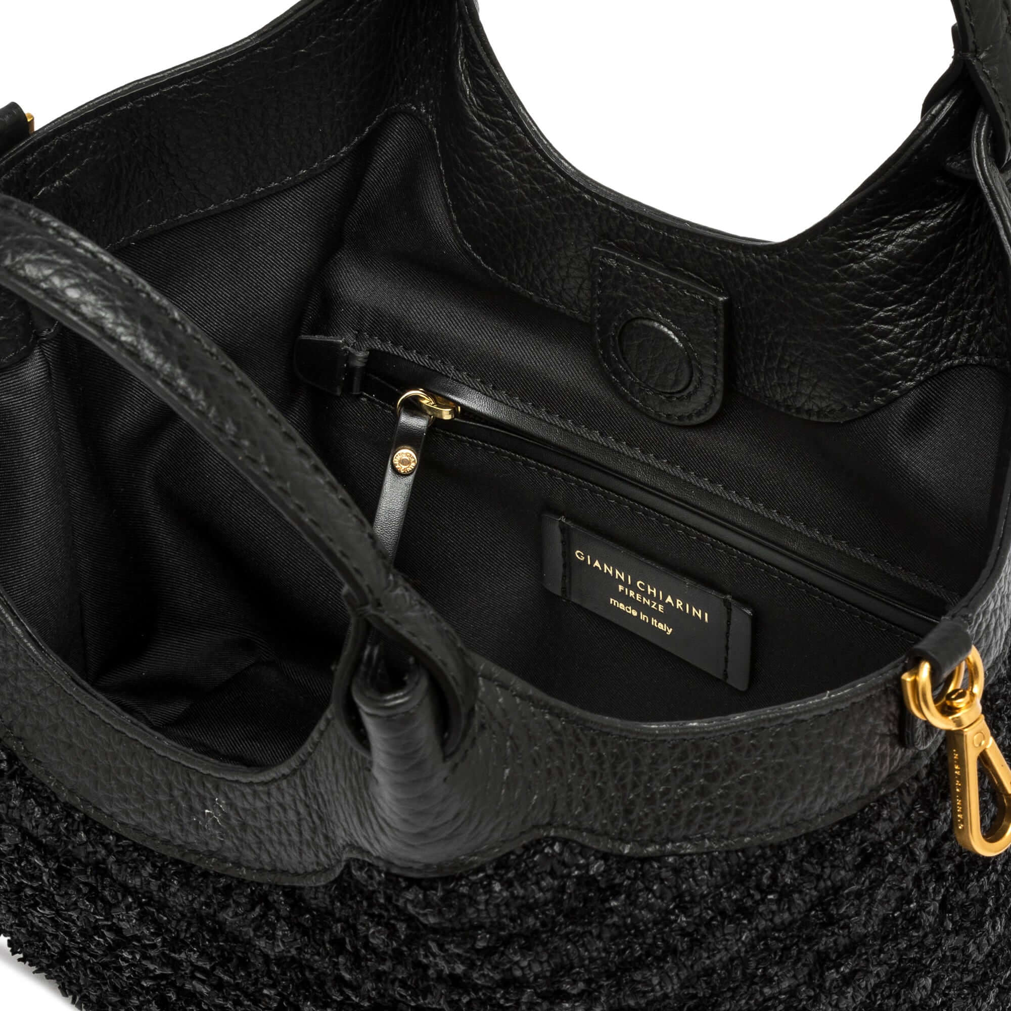 Interior view of a DUA handbag showcasing the black leather lining and gold zipper pocket.