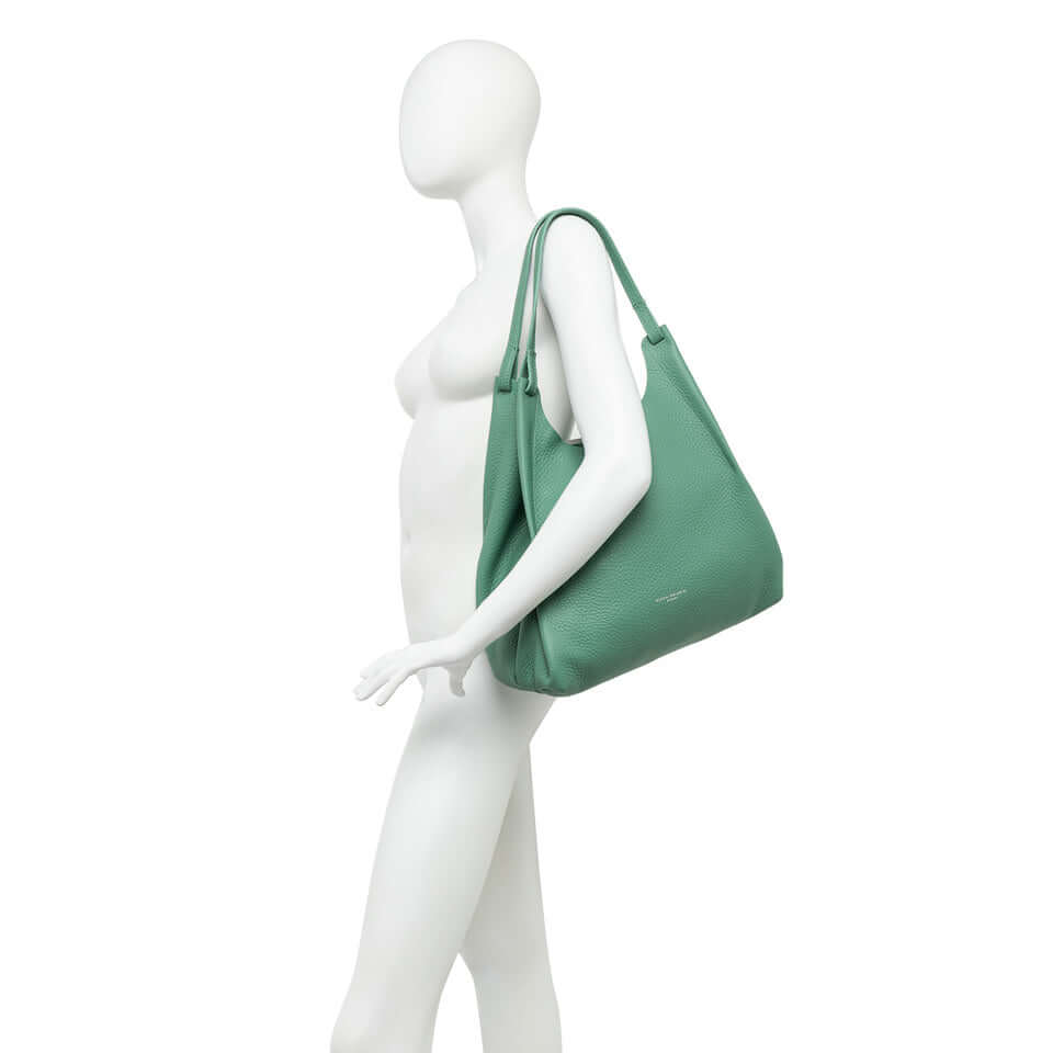 Stylish DUA handbag in green displayed on a mannequin, featuring double-grain leather and practical design.