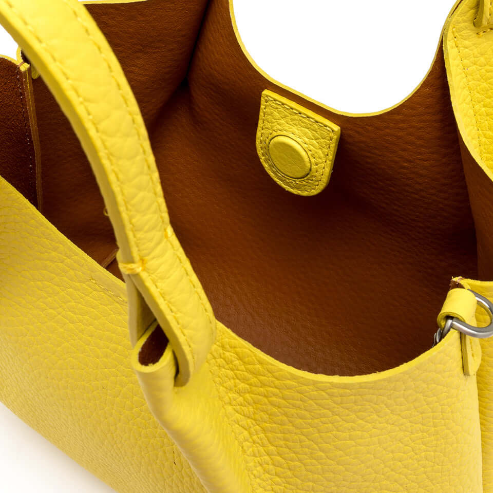 Interior view of a vibrant yellow leather bag with a smooth lining and stylish design details.