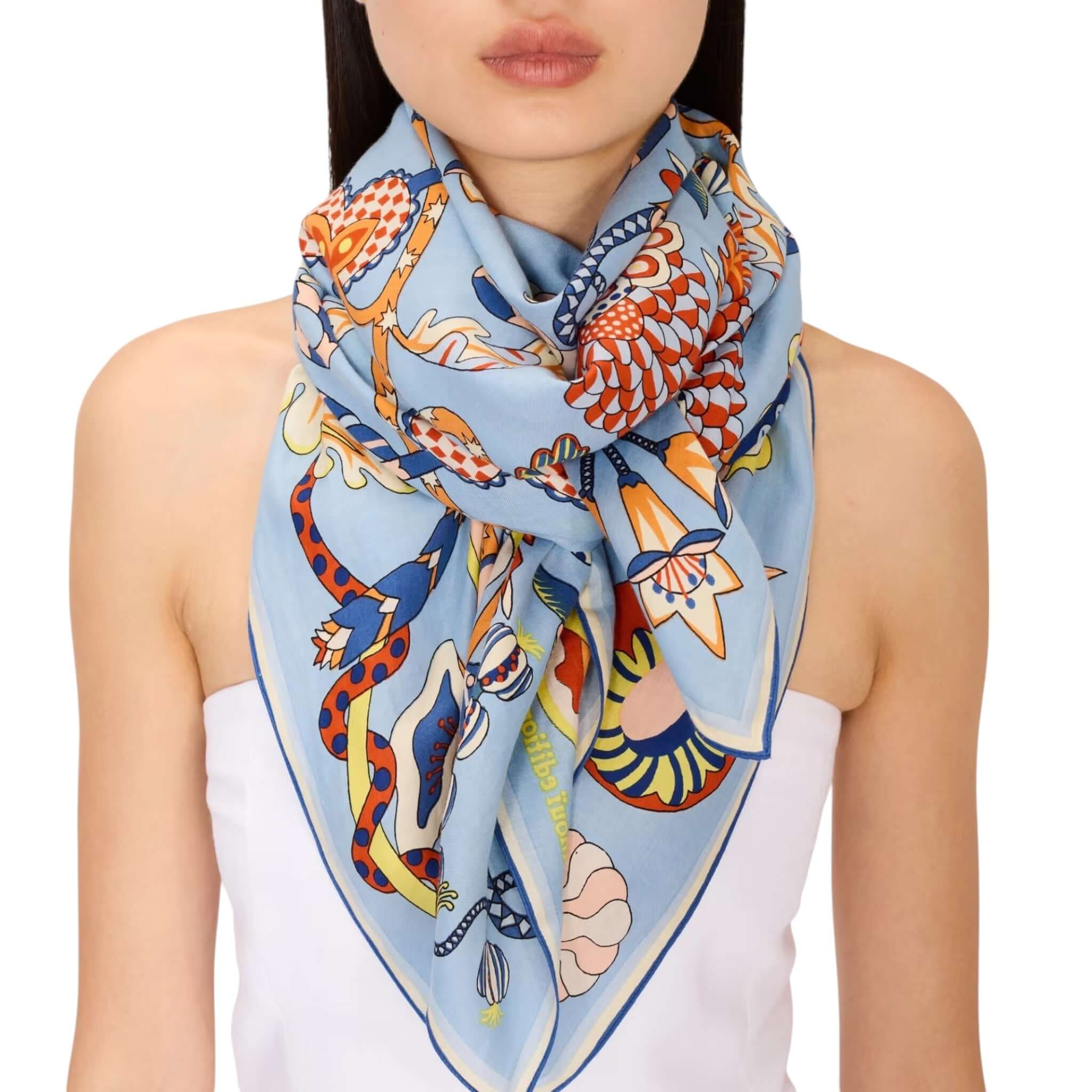 Foulard Quadrato Botanique indossato, presenta un design colorato e dettagliato su sfondo blu, ideale per ogni occasione.