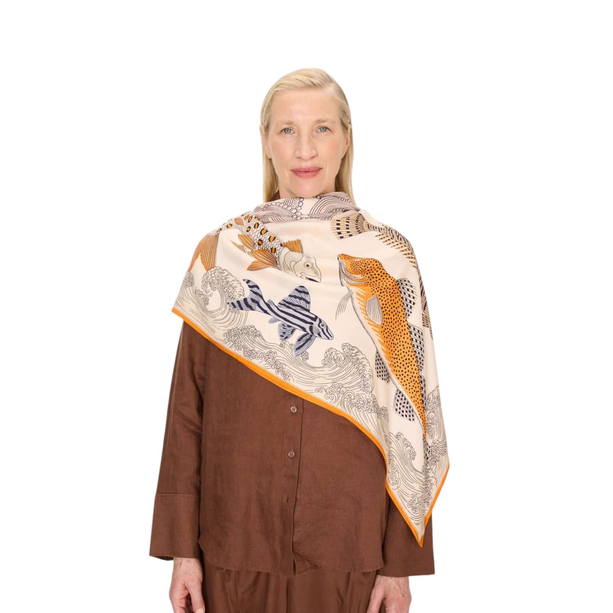 Elegant woman wearing the Foulard Quadrato Poseidon scarf, featuring vibrant fish designs on soft modal silk.