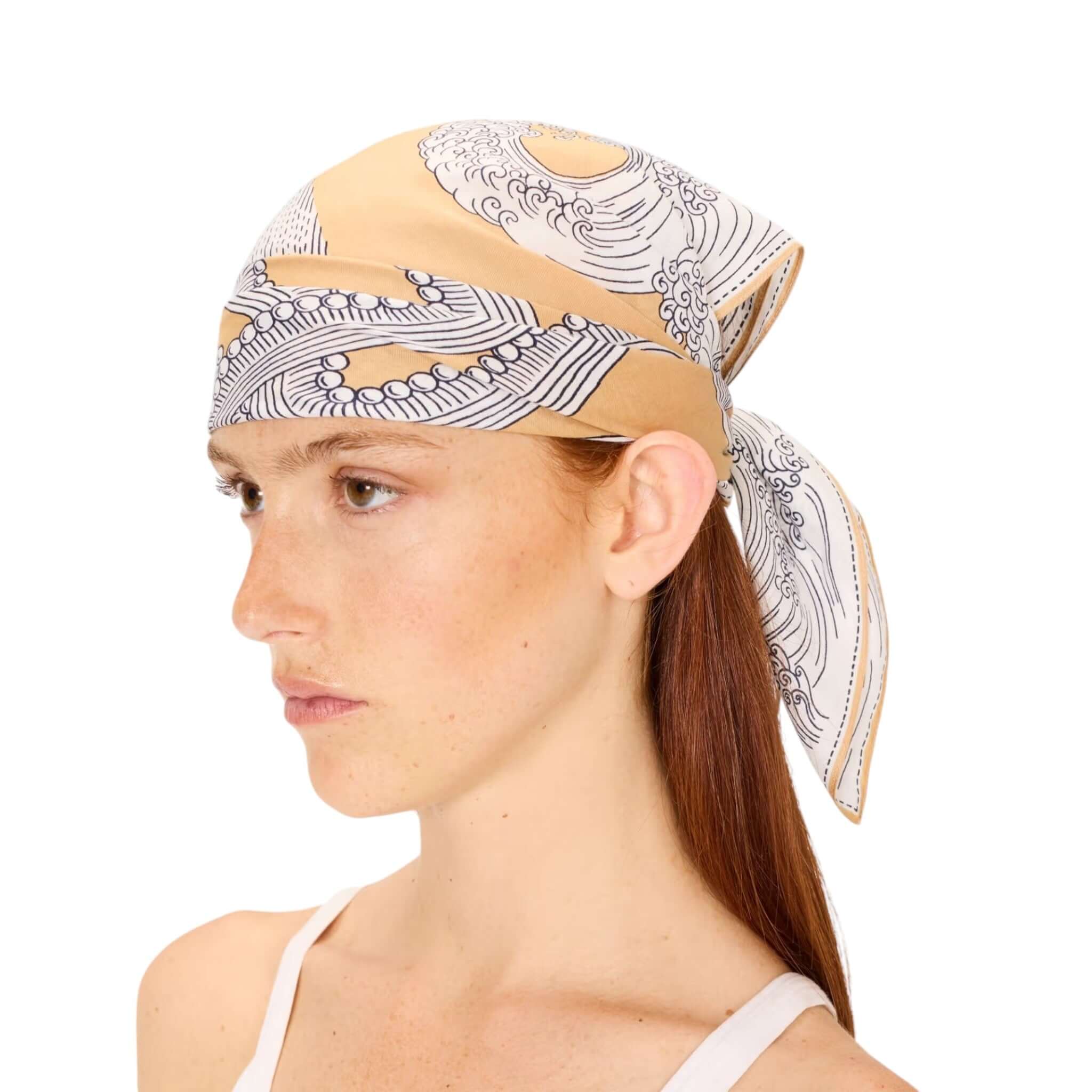 Model wearing Foulard Quadrato Poseidon scarf tied in hair, showcasing its unique design and colors.