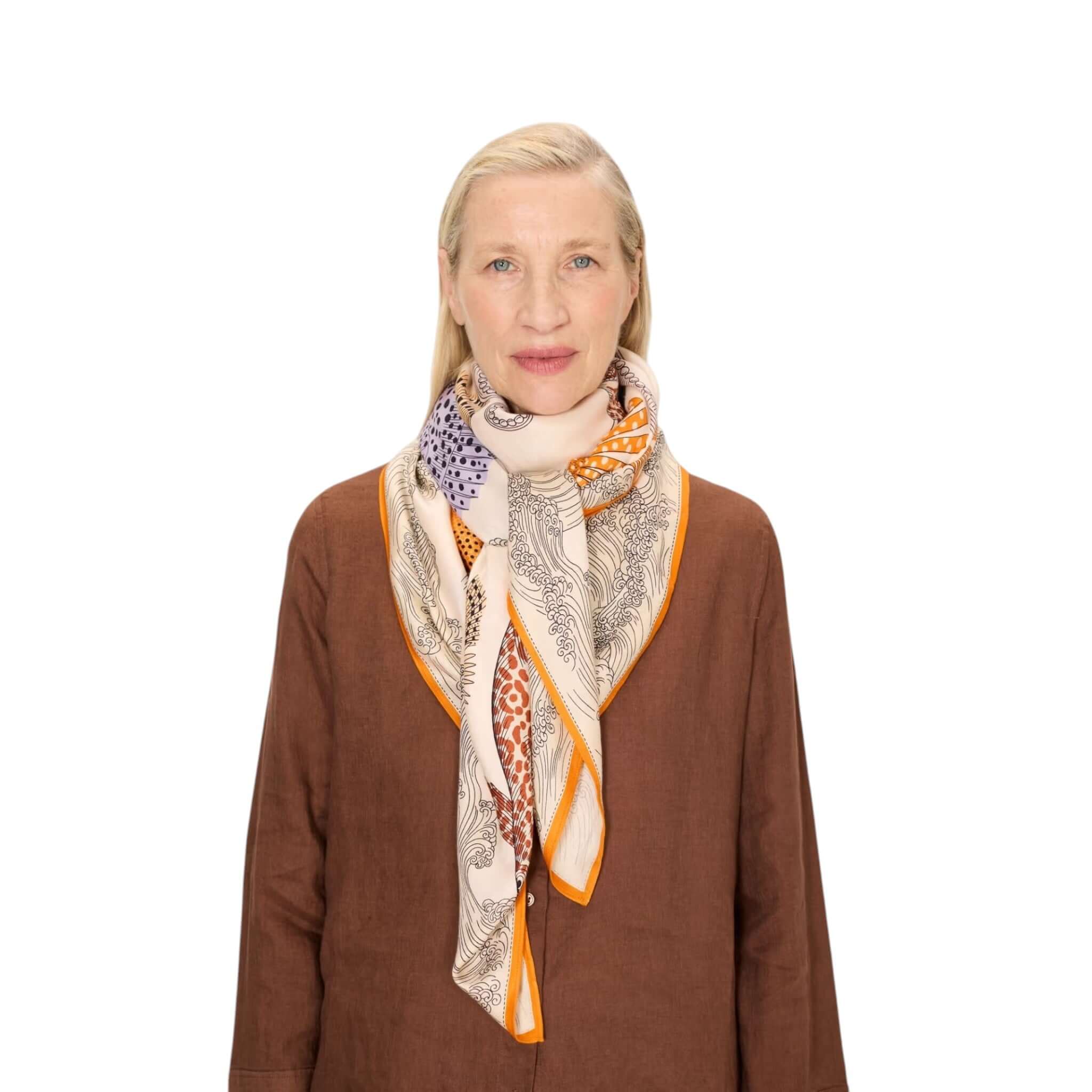 Foulard Quadrato Poseidon in seta modal indossato da donna, con design colorato e drappeggio elegante.