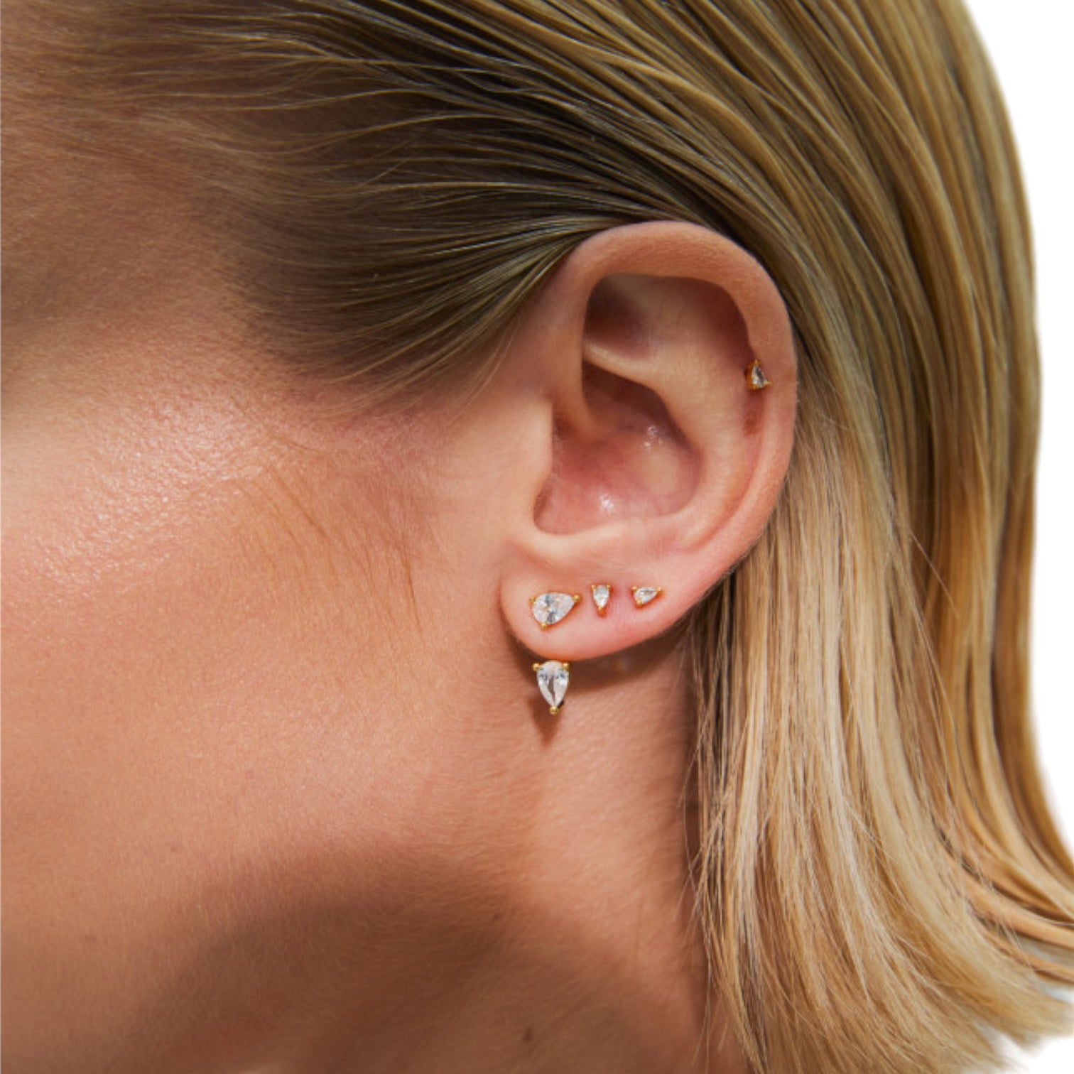 Close-up of a model wearing multiple stud earrings made of brass and 18k gold plating.