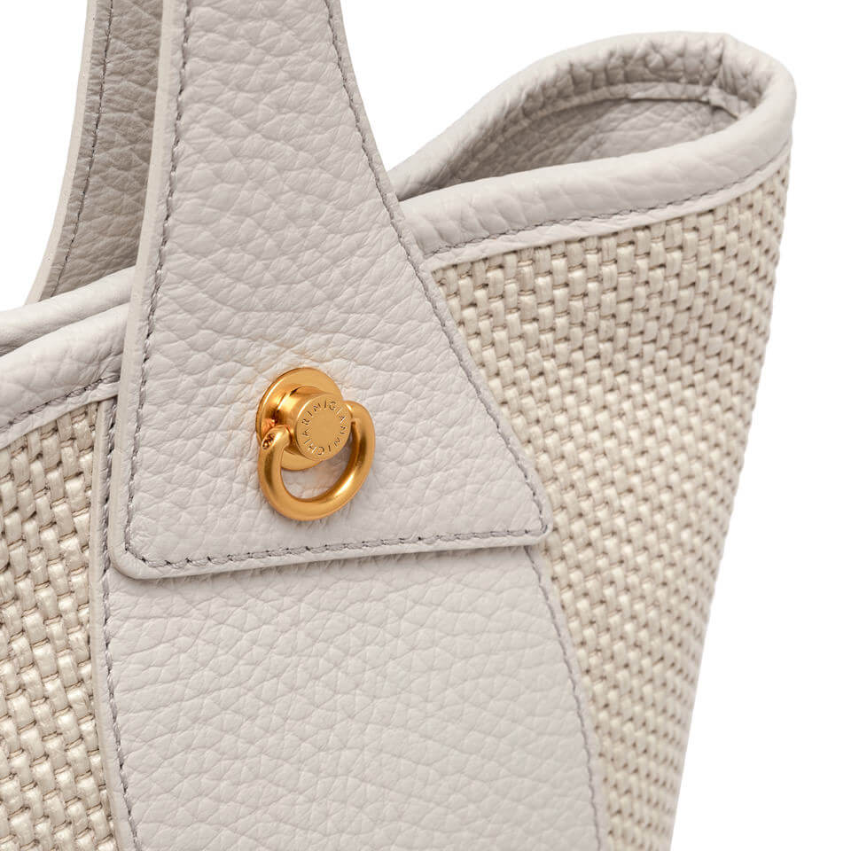 Close-up of Gianni Chiarini Firenze Ester handbag, featuring woven straw fabric and decorative gold piercing detail.