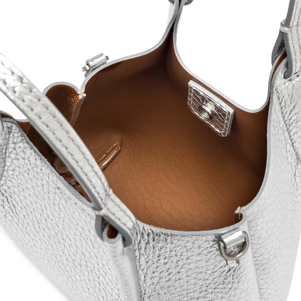 Interior view of the DUA handbag featuring sleek silver leather and a magnetic closure.