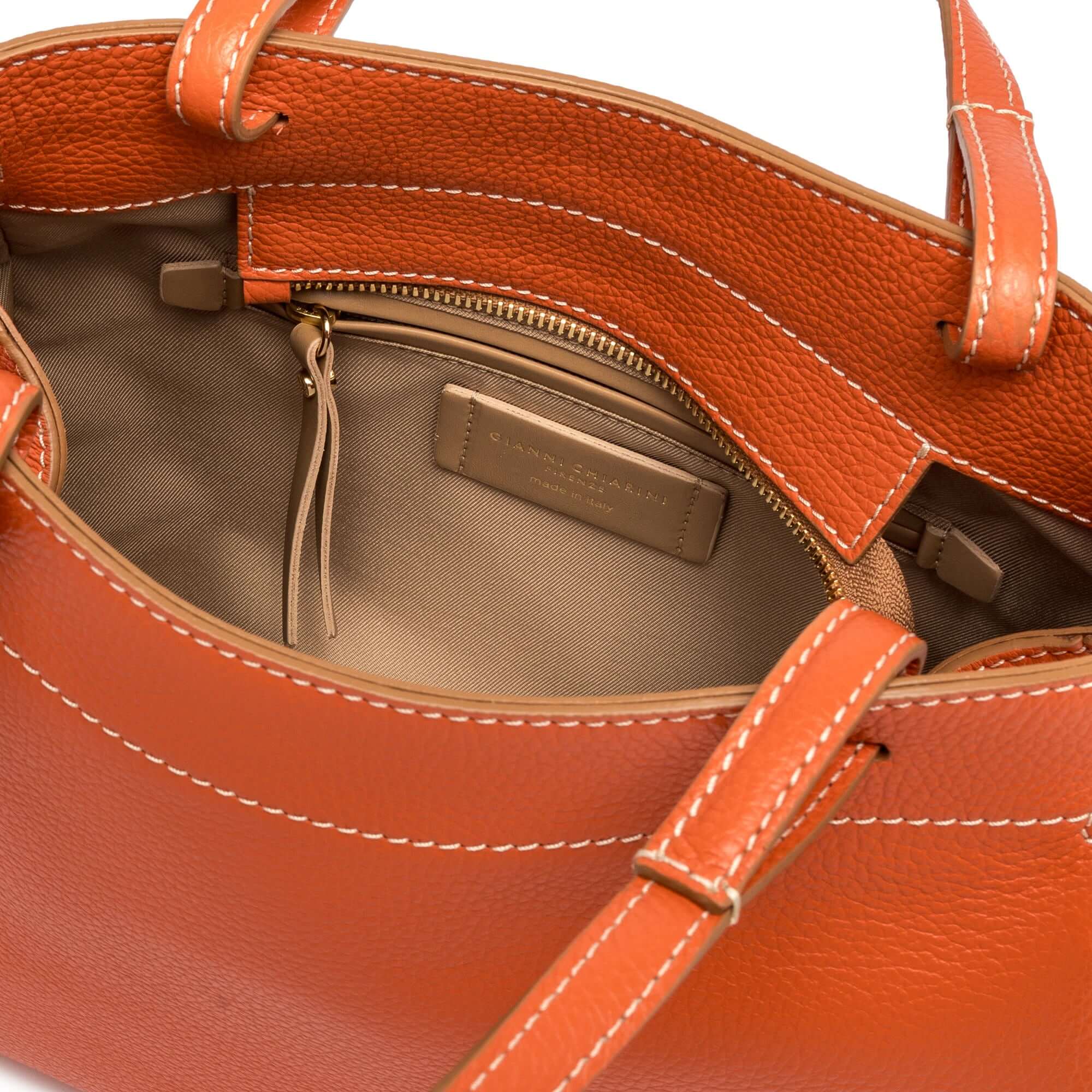 Interior view of the Ottavia bag by Gianni Chiarini Firenze, featuring orange pebbled leather and a zippered pocket.