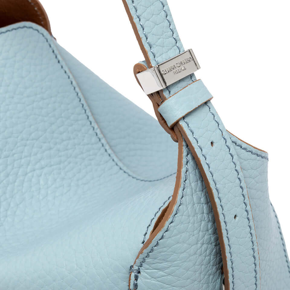 Close-up of Penelope bag's light blue leather texture and adjustable strap detail.