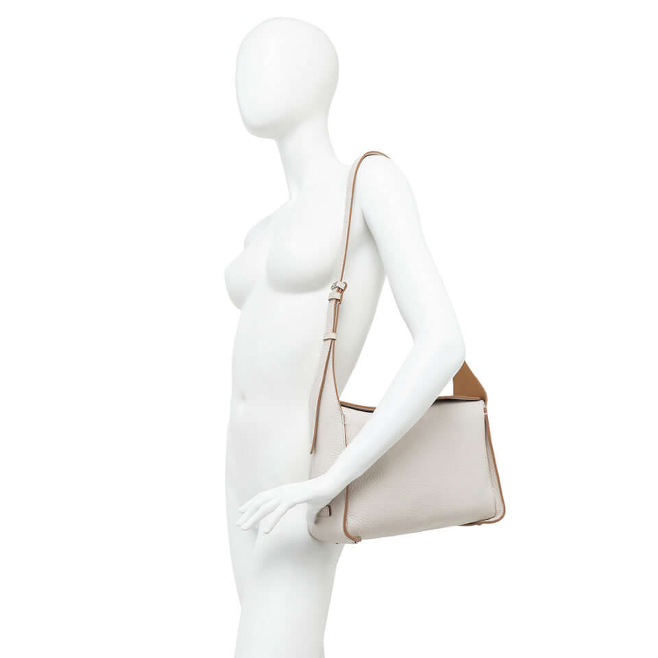 Elegante borsa PENELOPE in pelle con tracolla regolabile, modello a scatola, su manichino bianco minimalista.
