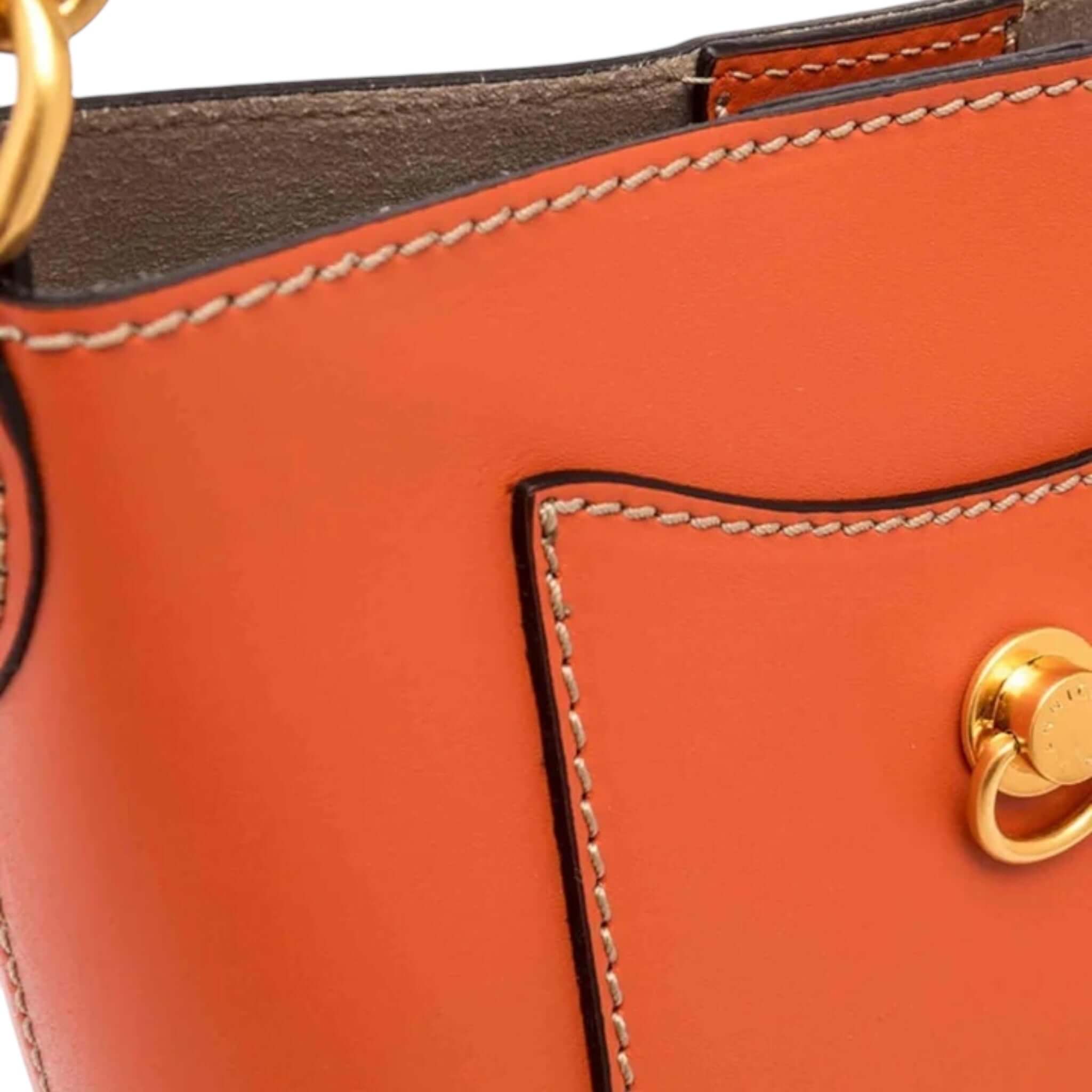 Close-up of Rubina handbag by Gianni Chiarini Firenze in orange leather featuring gold button detail.