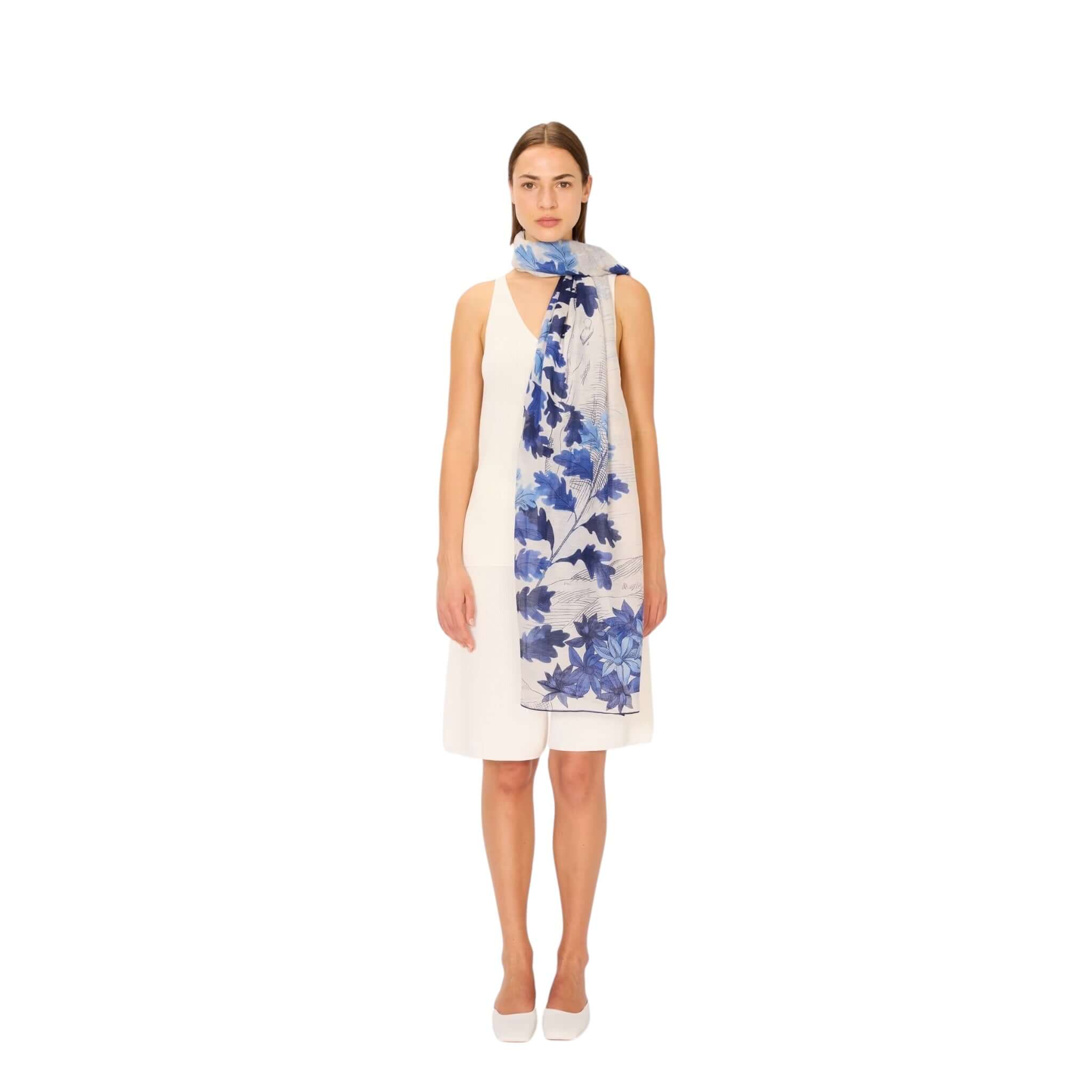 Sciarpa Amboise in tessuto leggero, colorata con design floreale blu, indossata da una modella su sfondo bianco.