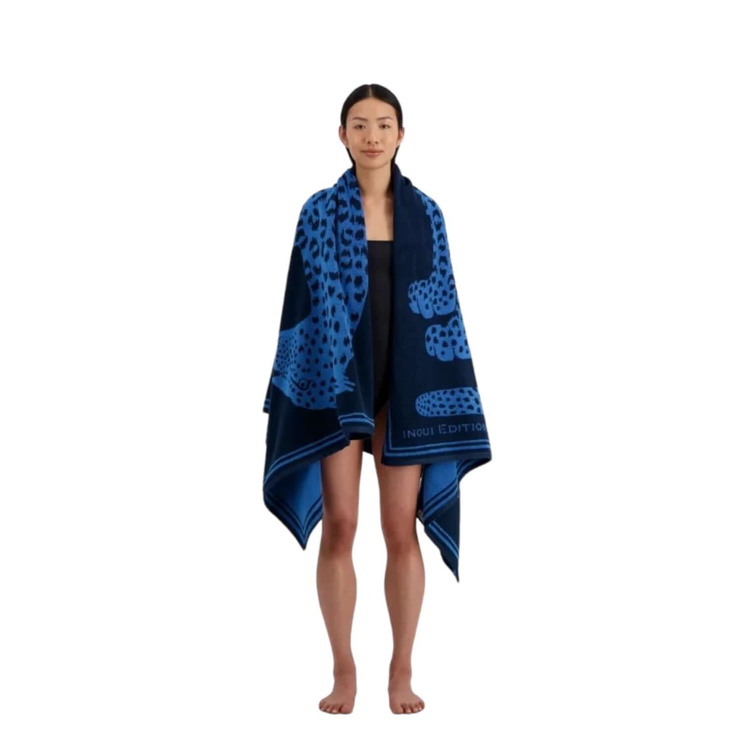 Model draped in Telo Mare Fetiche towel featuring hand-drawn illustrations, 100% cotton, vibrant blue and black design.