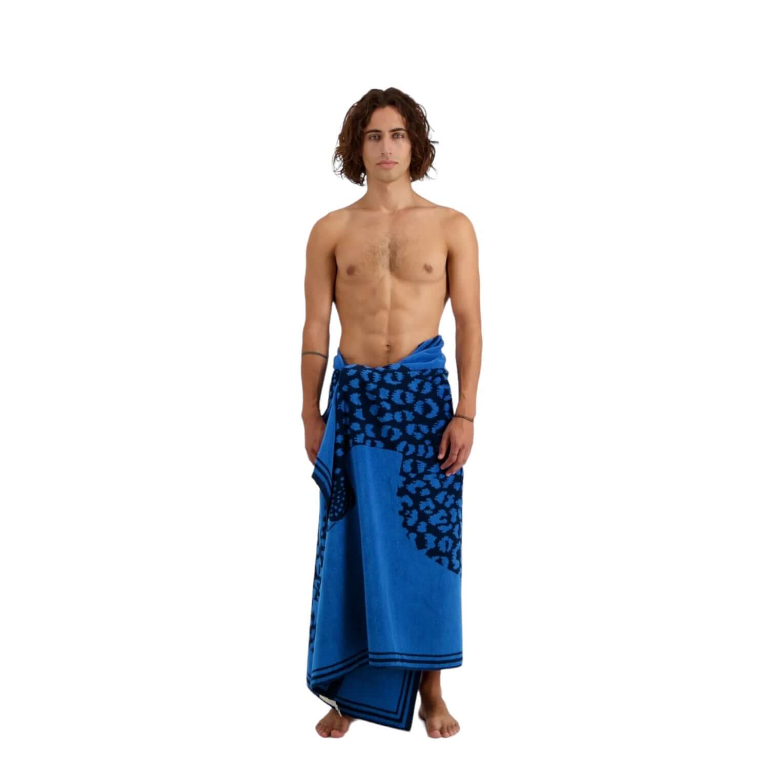 Man wrapped in a blue Telo Mare Fetiche beach towel featuring hand-drawn illustrations, perfect for beach moments.