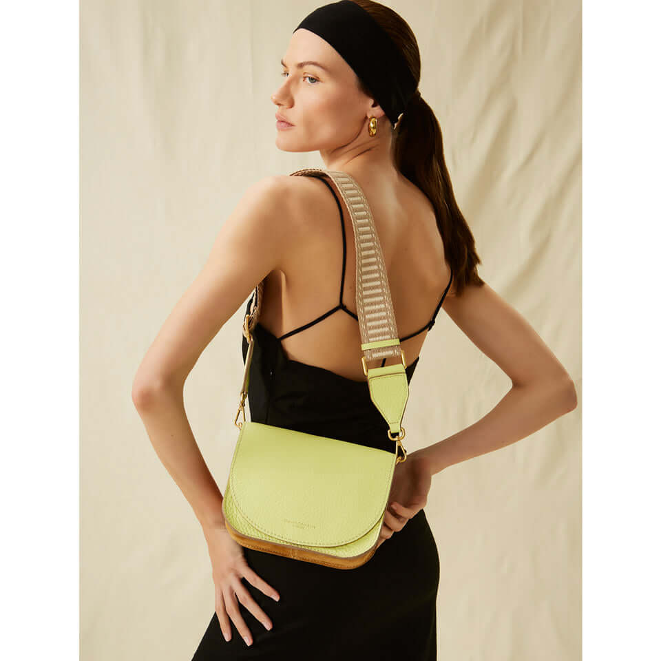 Modella che indossa la borsa TARA di Gianni Chiarini, in pelle gialla con tracolla a spiga.