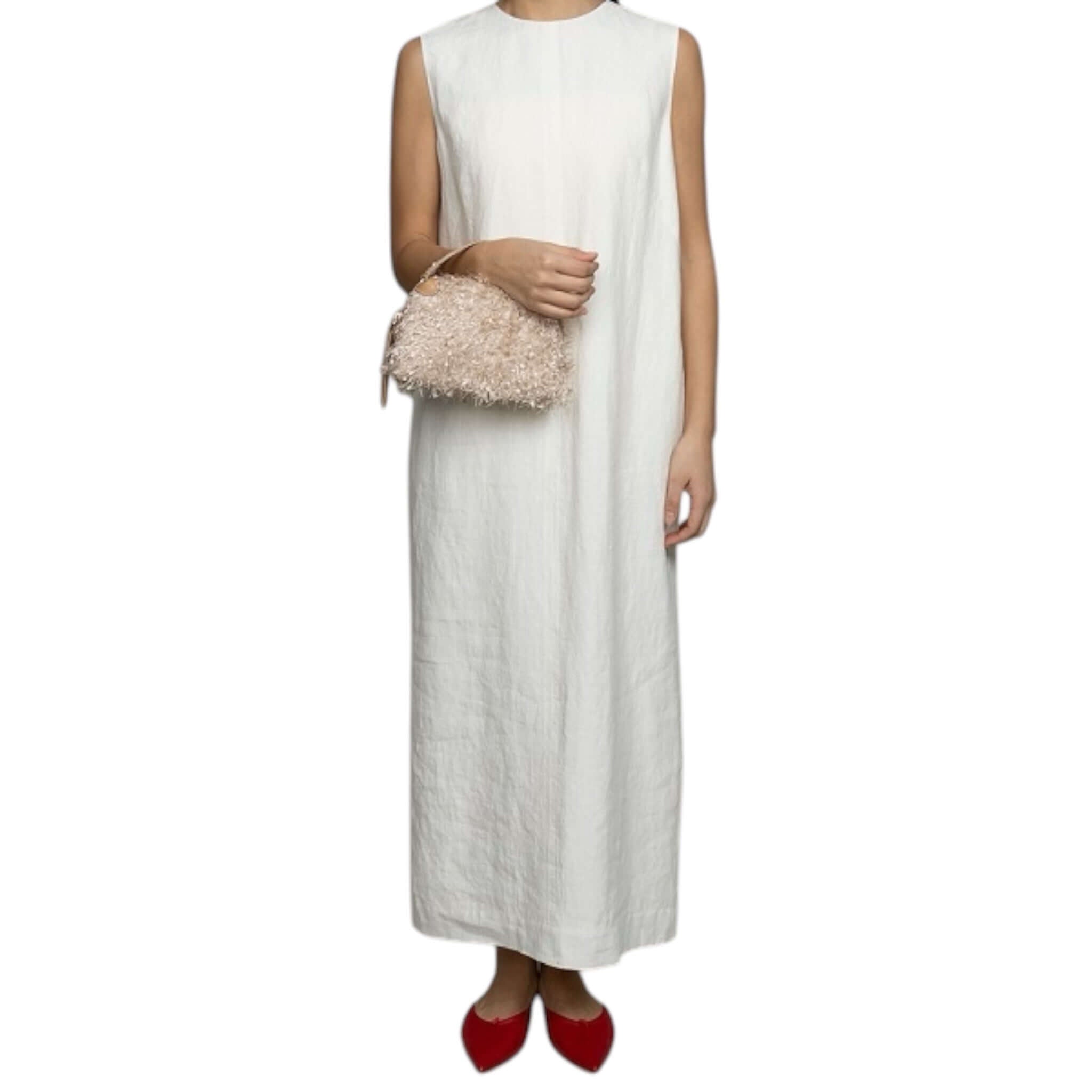 Modella che indossa un vestito bianco lungo luminoso con borsa Alifa di Gianni Chiarini e scarpe rosse.