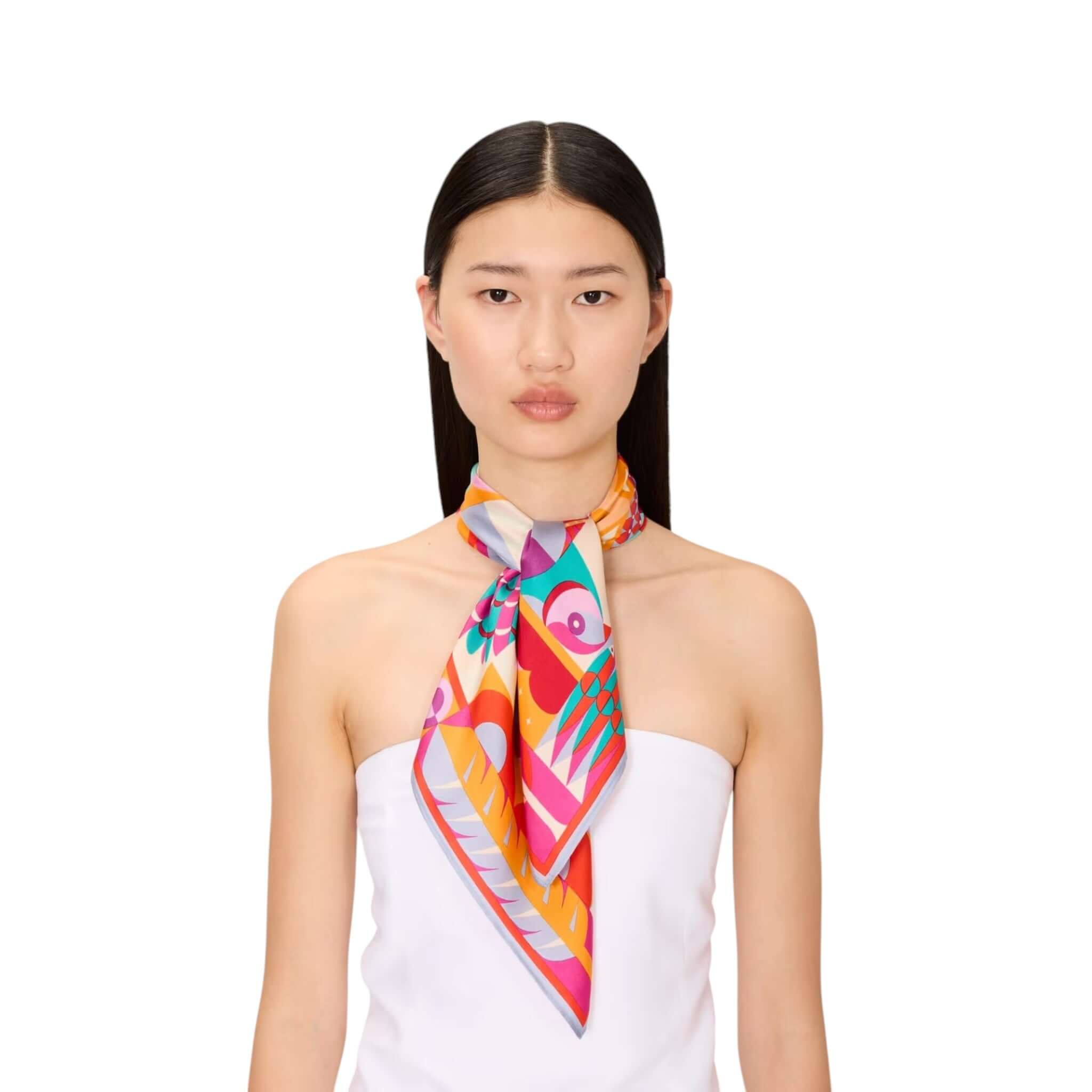 Model wearing the Foulard Quadrato Cleo, a colorful silk scarf styled around the neck, showcasing its vibrant design.