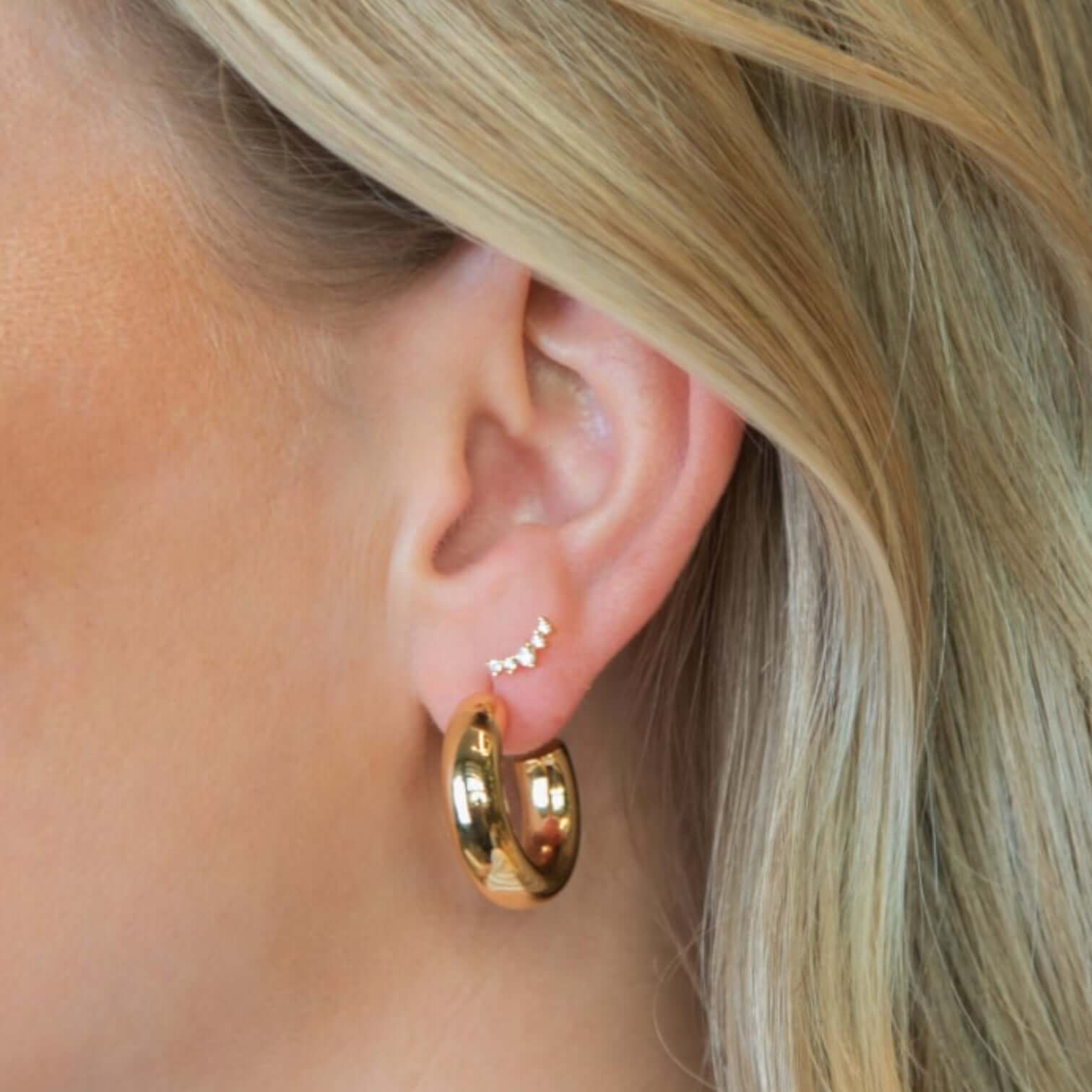 Elegant gold-plated brass hoop earrings showcased on a model's ear, highlighting their sleek design.