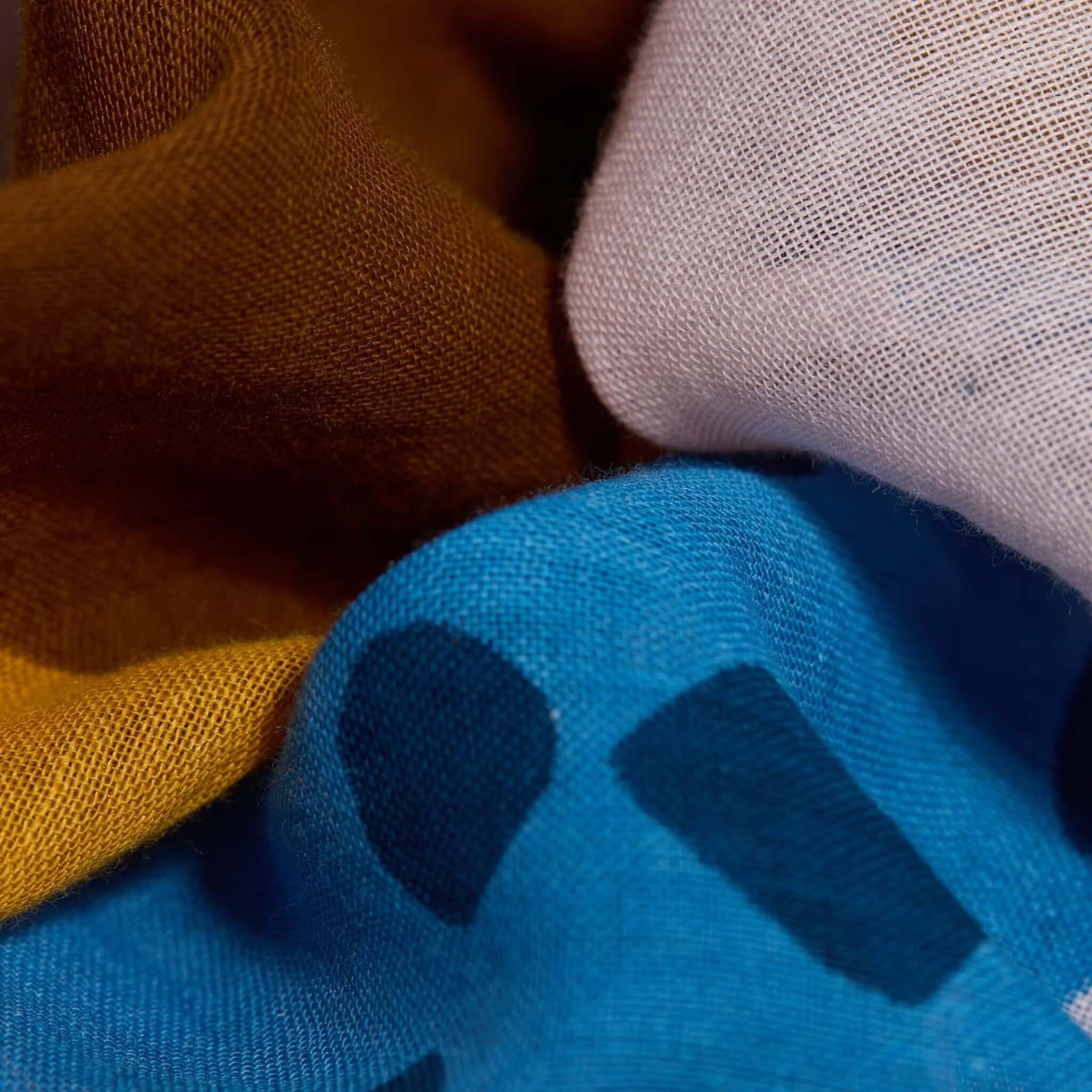 Close-up of colorful cotton scarves in various patterns and colors, showcasing the texture and vibrant designs.