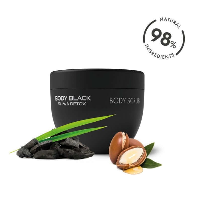 Body Black Body Scrub with natural ingredients, 250ml jar surrounded by charcoal, nuts, and green leaves.